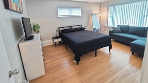A bedroom with a bed, a sofa, a desk, and a window. - The Rooftop - Haven! (Waukegan)