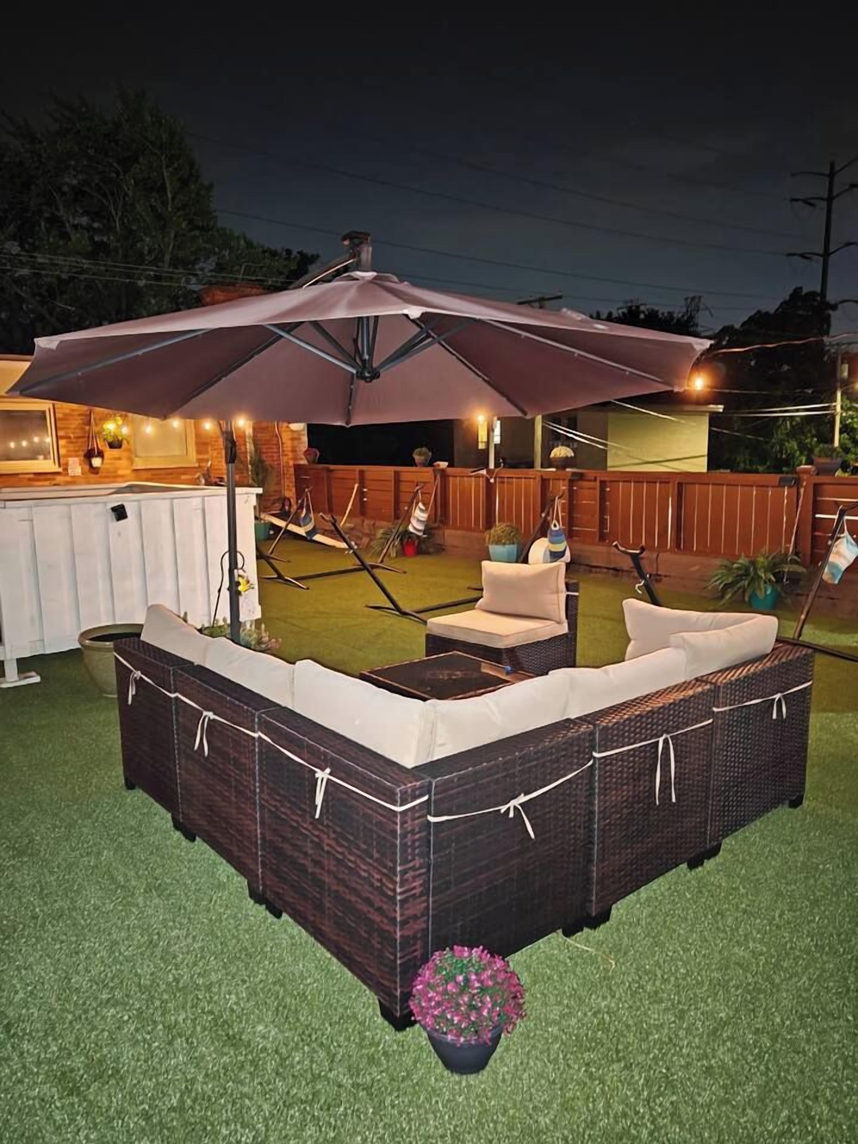 An outdoor seating area with a large umbrella, wicker furniture, and a small table.