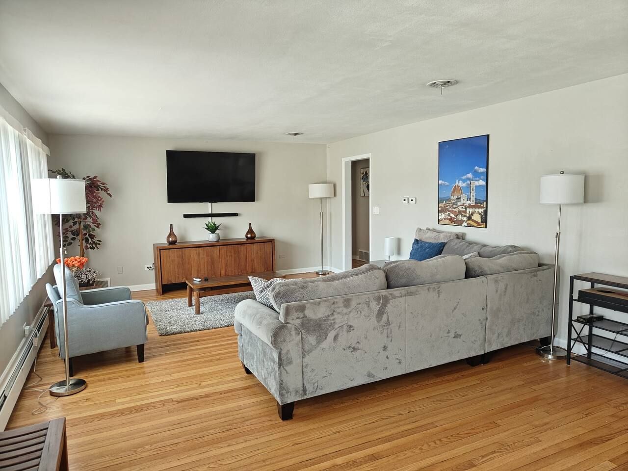 Un salon moderne avec un canapé gris, un téléviseur à écran plat et un plancher en bois.