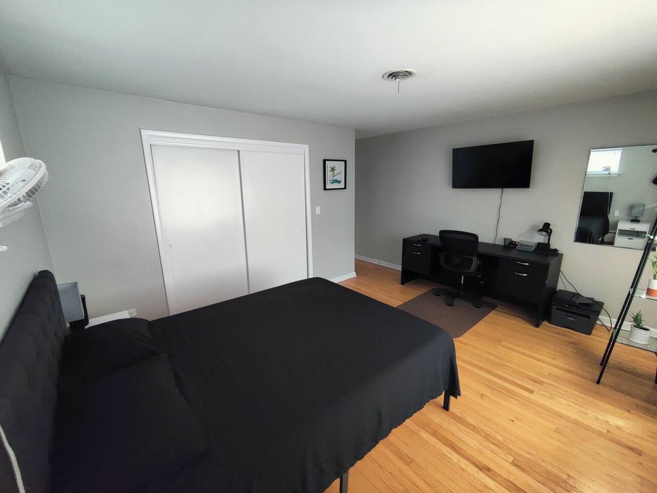 Une chambre à coucher comprenant un lit, un bureau, une chaise, une télévision et une armoire.