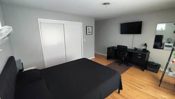 Une chambre à coucher comprenant un lit, un bureau, une chaise, une télévision et une armoire.