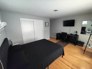 A bedroom with a bed, a desk, a chair, a television, and a wardrobe.