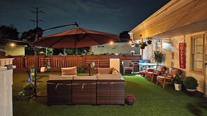 An outdoor patio with a wicker sofa, a table, and chairs.
