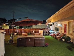 An outdoor patio with a wicker sofa, a table, and chairs.