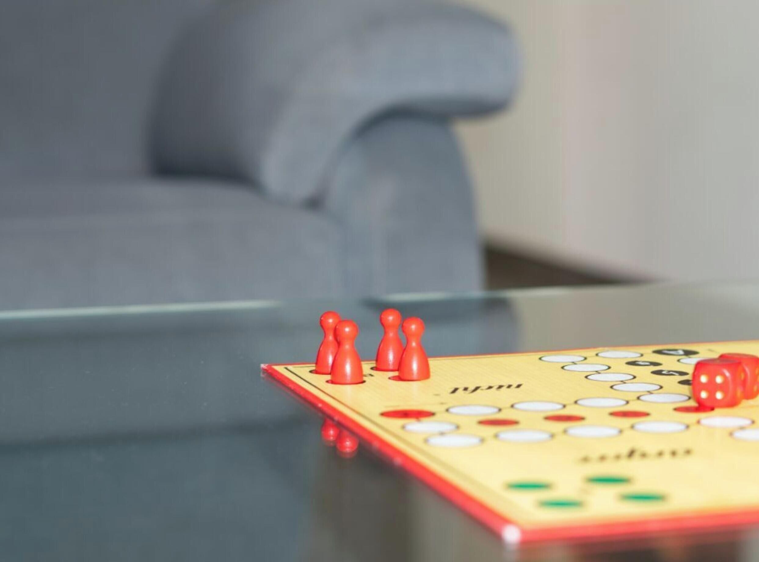 A close-up of a board game with red pieces on a glass table.