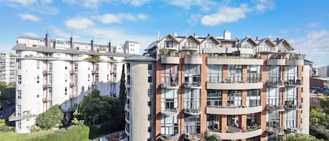 Un edificio residencial de varios pisos con balcones, piscina y jardín.