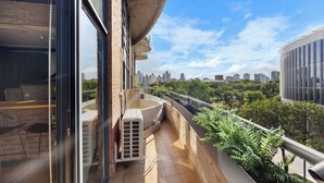 Ein moderner Balkon mit Stadtblick, einer eingebauten Sitzgelegenheit und einem kleinen Garten.