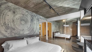 Ein modernes Hotelzimmer mit einem großen Bett, einem Spiegel und einer Ziegelwand.