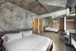 Ett modernt hotellrum med en stor säng, en spegel och en vägg av tegelsten.