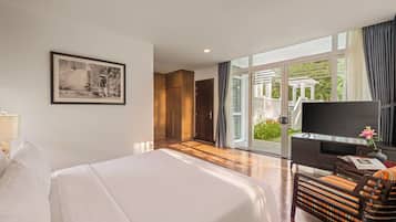 A hotel room with a bed, a desk with a TV, a chair, and a large window with curtains.