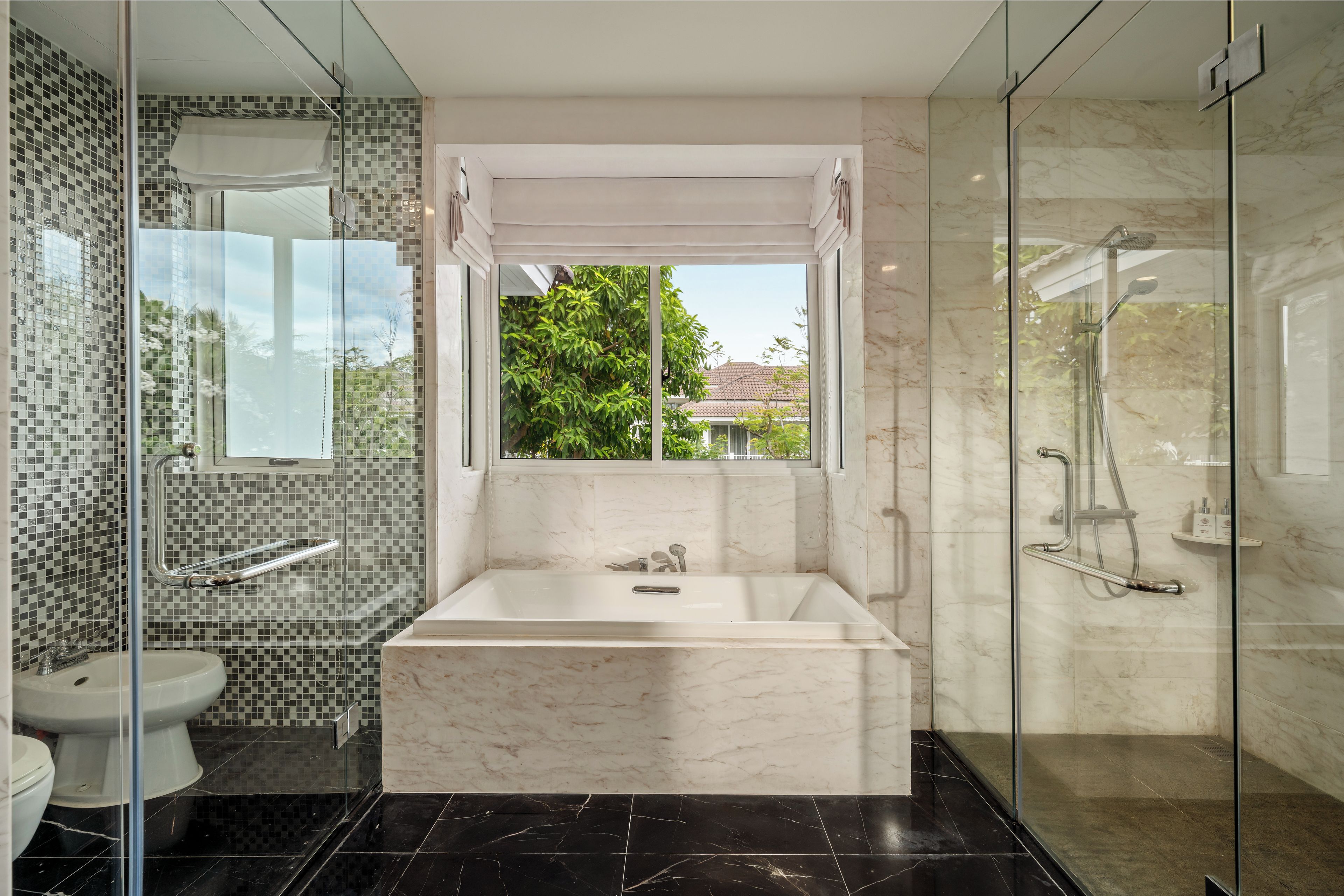 A modern bathroom with a glass-enclosed shower, a bathtub, and a toilet.