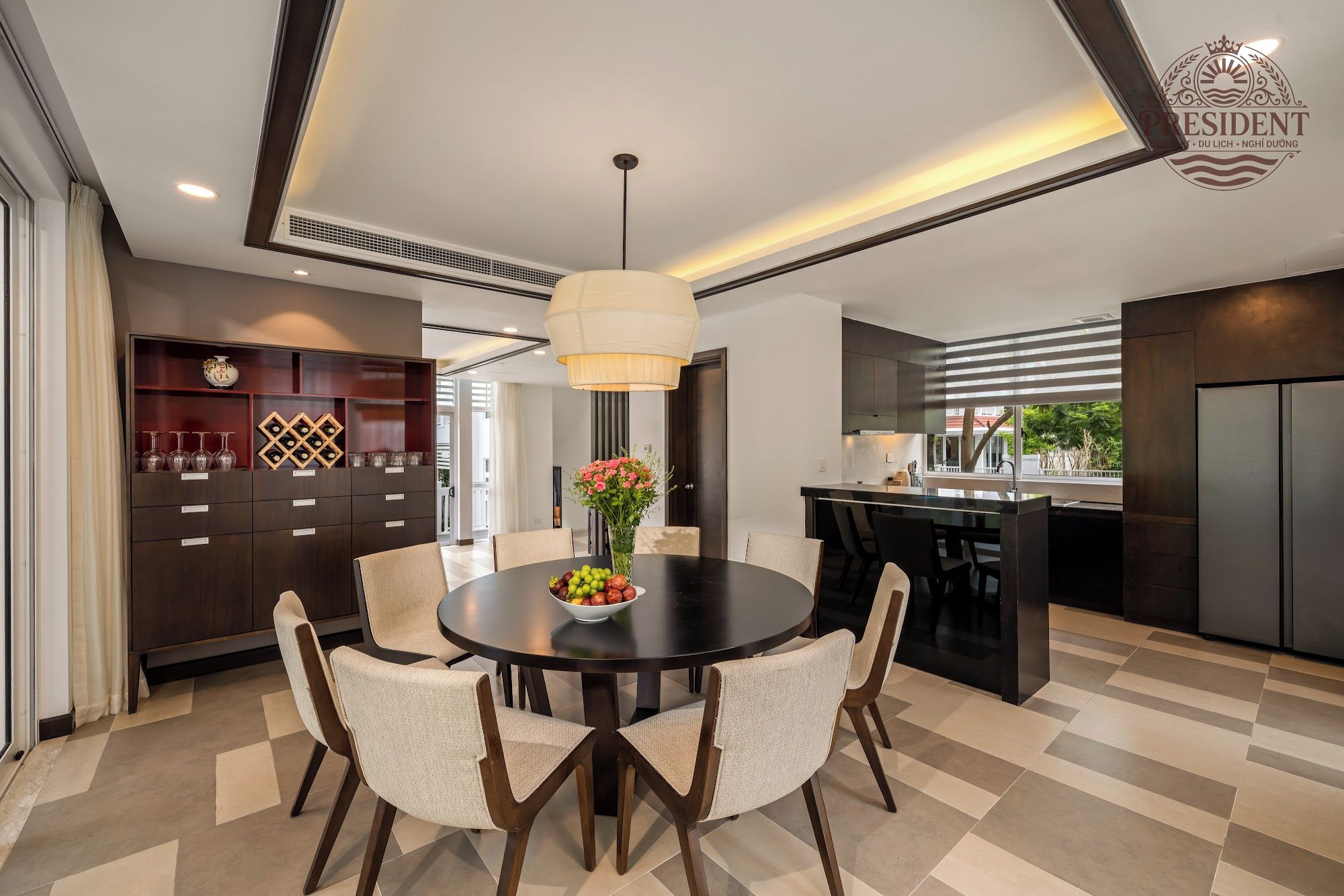 Una cocina moderna con una isla central, muebles oscuros y un comedor con una mesa redonda y sillas.