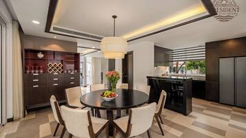 Una cocina moderna con una isla central, muebles oscuros y un comedor con una mesa redonda y sillas.