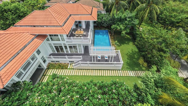 A multi-story house with a swimming pool, surrounded by lush greenery and palm trees. - President Garden Ocean Villa  (Da Nang Municipality)