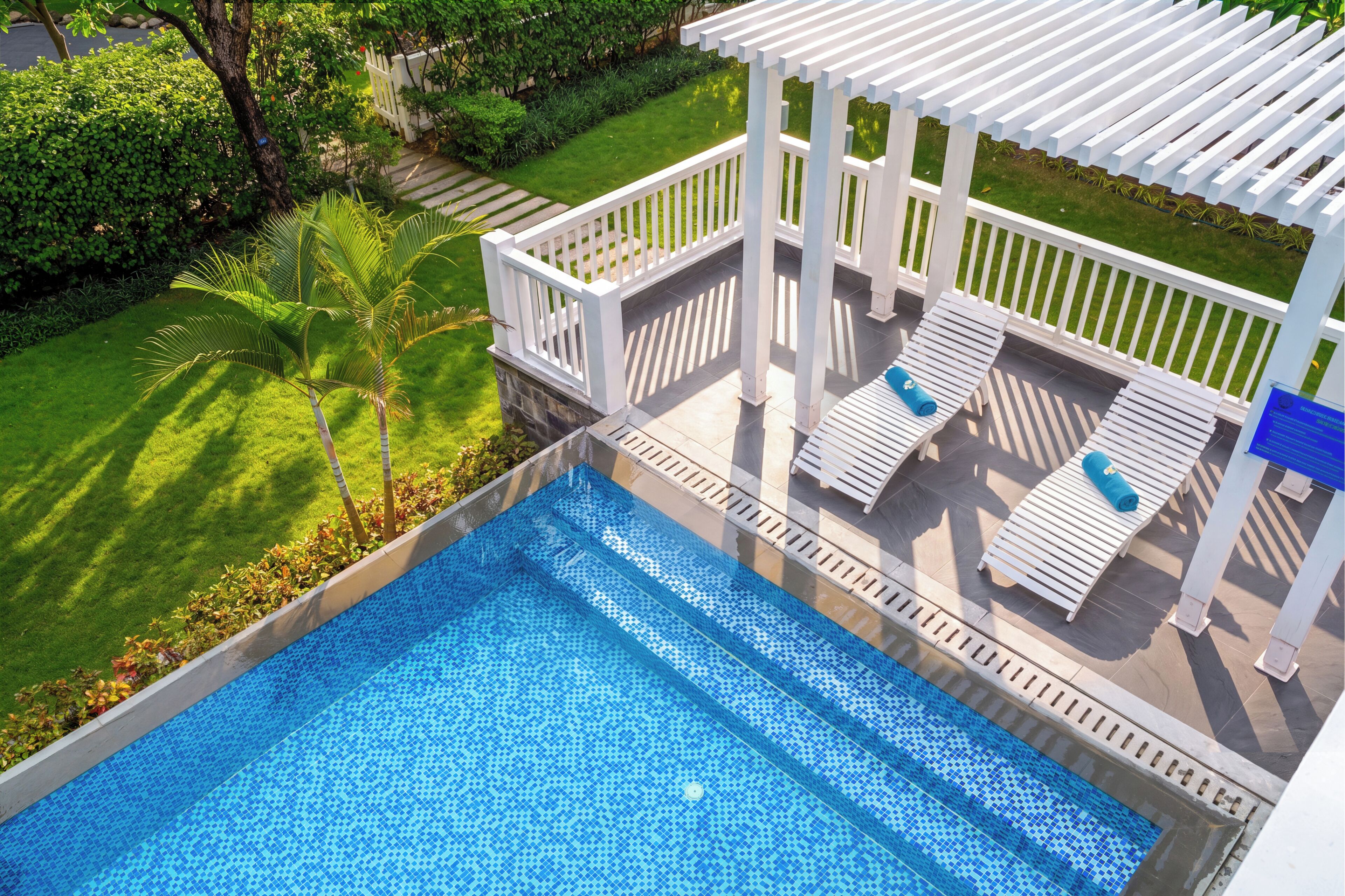 A rooftop pool with a clear view of the surrounding greenery and a white pergola structure.