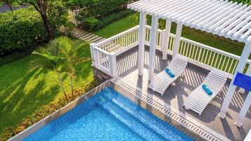 A rooftop pool with a clear view of the surrounding greenery and a white pergola structure.