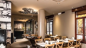 L’intérieur d’un restaurant, avec des chaises et des tables en bois, ainsi qu’un luminaire décoratif au plafond.