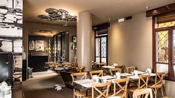 Interior de restaurante com cadeiras e mesas de madeira, e luminária decorativa no teto.