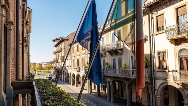 Une rue bordée d’immeubles, un ciel dégagé et un drapeau.