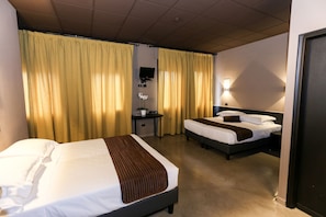 Een hotelkamer met twee bedden, een bureau, een stoel, een televisie en gordijnen.