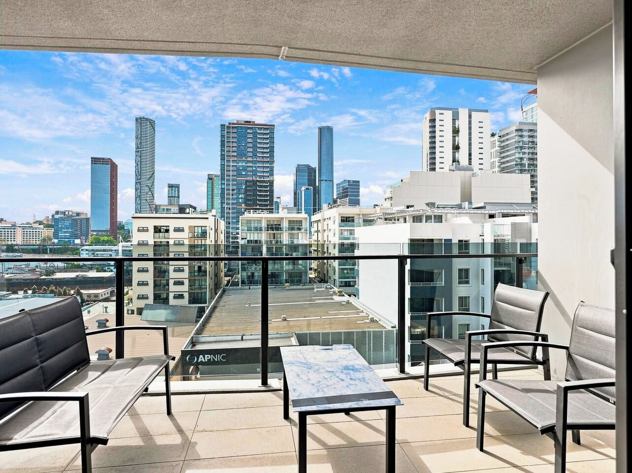 A balcony with seating, a table, and a city view.