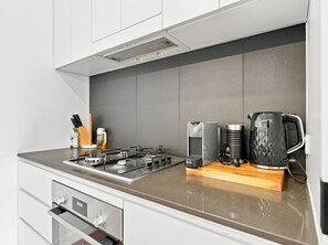 Eine moderne Küche mit Gaskochfeld, Kaffeemaschine und Wasserkocher auf der Arbeitsfläche.