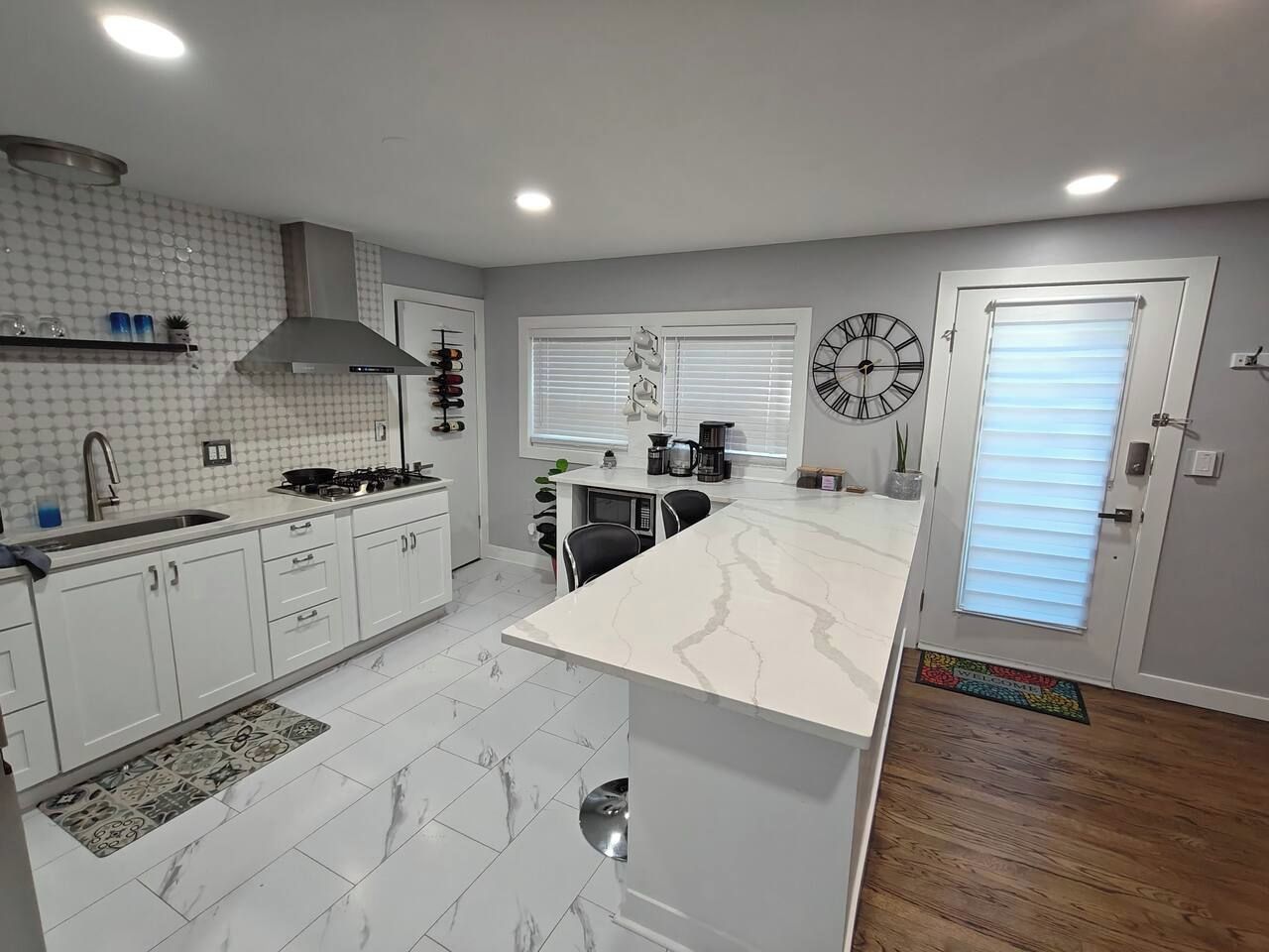 A modern kitchen with white cabinets, a marble countertop, and a built-in stove.