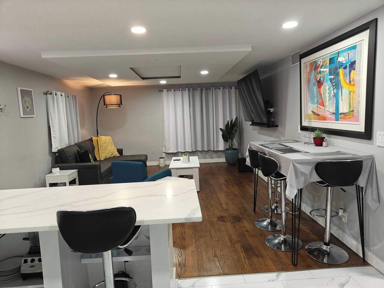 Un intérieur moderne comprenant un coin repas, un canapé et un grand tableau abstrait accroché au mur.
