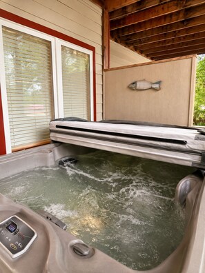 Un jacuzzi con panel de control, techo de madera y decoración de pez en la pared.