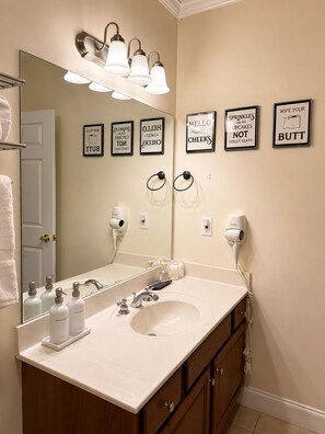 Un baño con un espejo grande, un lavabo y un secador de pelo montado en la pared.