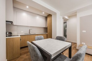 Une cuisine moderne dotée de meubles encastrés, d’un mur d’accent en bois et d’un coin repas avec une table et des chaises.