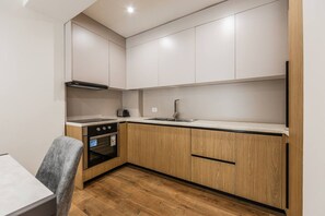 Eine kleine Küche mit Holzausstattung, einem eingebauten Backofen und einer Arbeitsplatte.