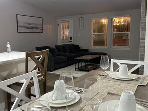 A dining area with a table set for four, a sofa, and a water bottle on a counter. - Charming Country Home! (Azle)