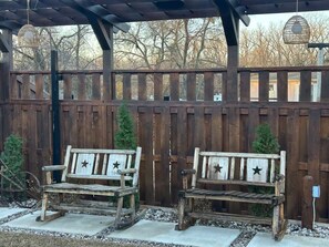 Two rustic wooden benches under a wooden pergola with a wooden fence in the background. - Charming Country Home! (Azle)