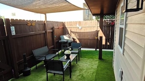 A backyard with a patio area, a wooden fence, and a lawn. - The Modern Loft & Patio (Waukegan)