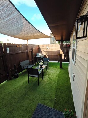 Un patio trasero con zona de estar, cerca de madera y césped.