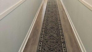 A hallway with framed pictures on the walls, a patterned carpet, and a hanging light fixture. - The Modern Loft & Patio (Waukegan)