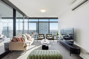 A modern living room with a sofa, armchairs, a coffee table, and a television.