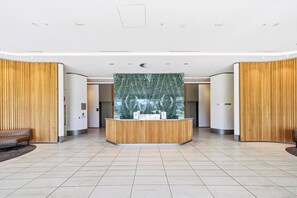 Ett modernt receptionsområde med en vägg av marmor, träpanel och en receptionsdisk.