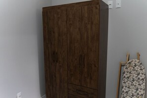 A wardrobe with a dark wood finish, a small drawer, and a hanging rod with a floral pattern. - CONDOMINIO SONHARE - 101 (ANAPOLIS)