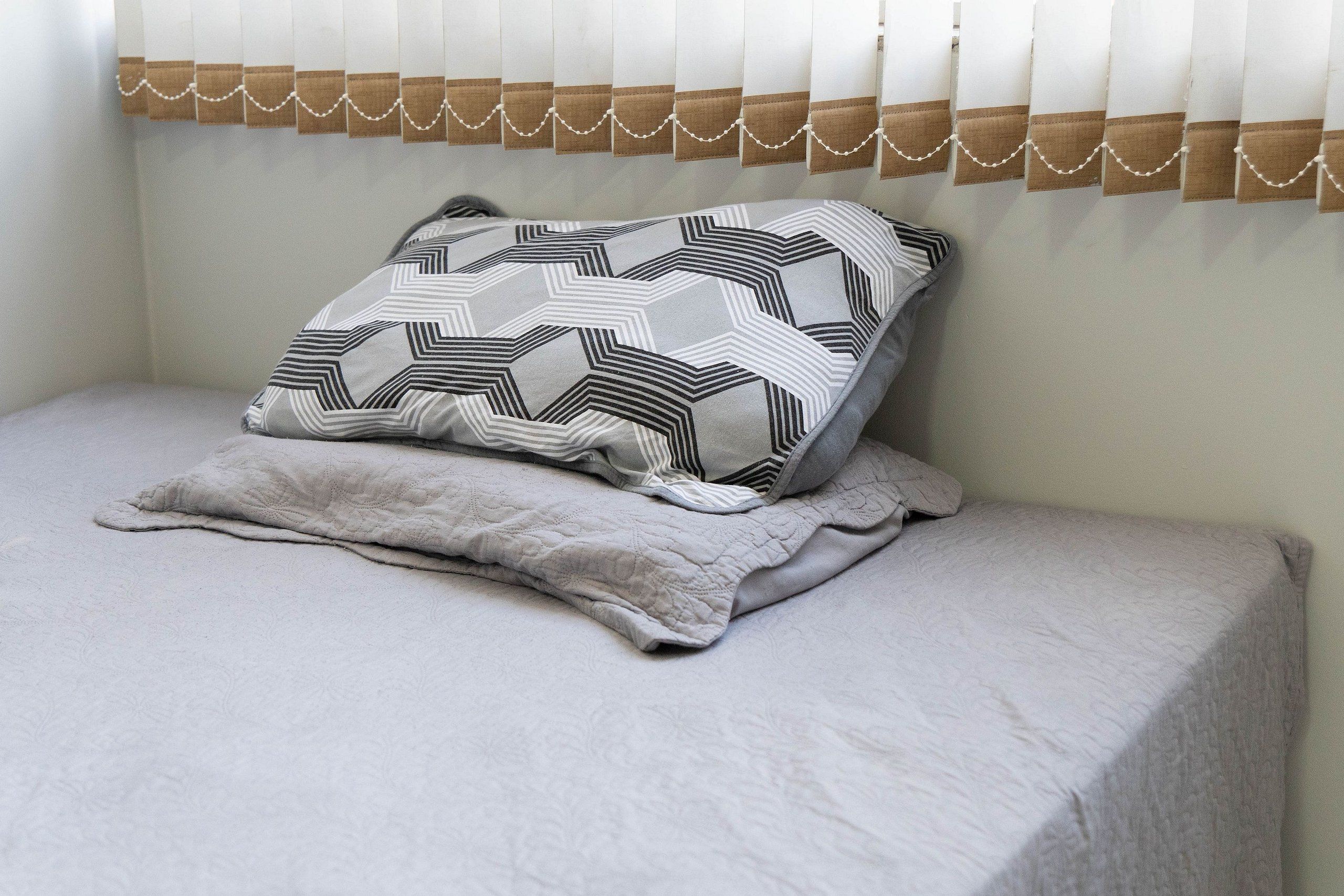 A bed with a patterned pillow and a quilted blanket.