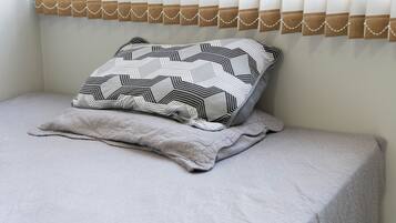 A bed with a patterned pillow and a quilted blanket.