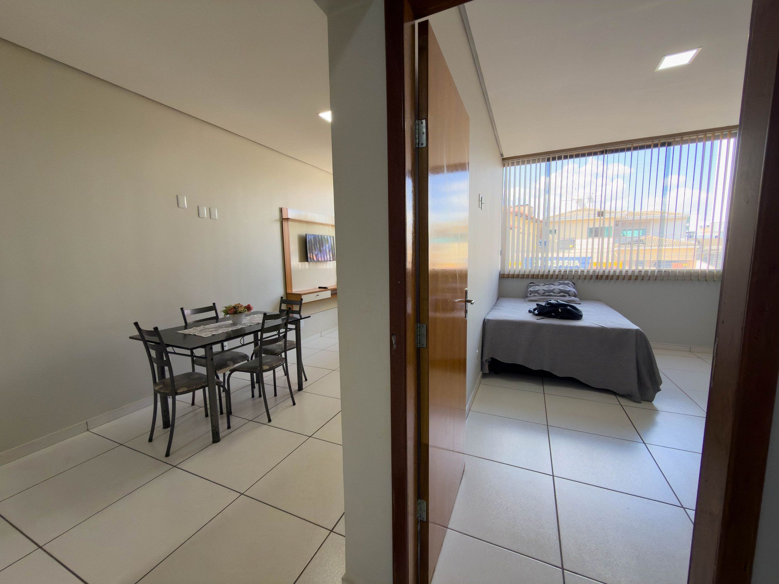 Ein Zimmer mit einem Bett, einem Tisch mit Stühlen und einem Fenster mit Jalousien.
