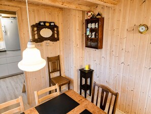 Una stanza con rivestimenti in legno, un tavolo da pranzo, sedie, una sveglia e un armadietto con stoviglie.