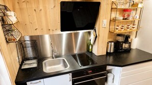 Een moderne keuken met een dubbele spoelbak, roestvrijstalen apparatuur en een koffiezetapparaat.