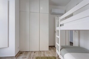 Une chambre avec un lit superposé, une armoire et un appareil de climatisation.