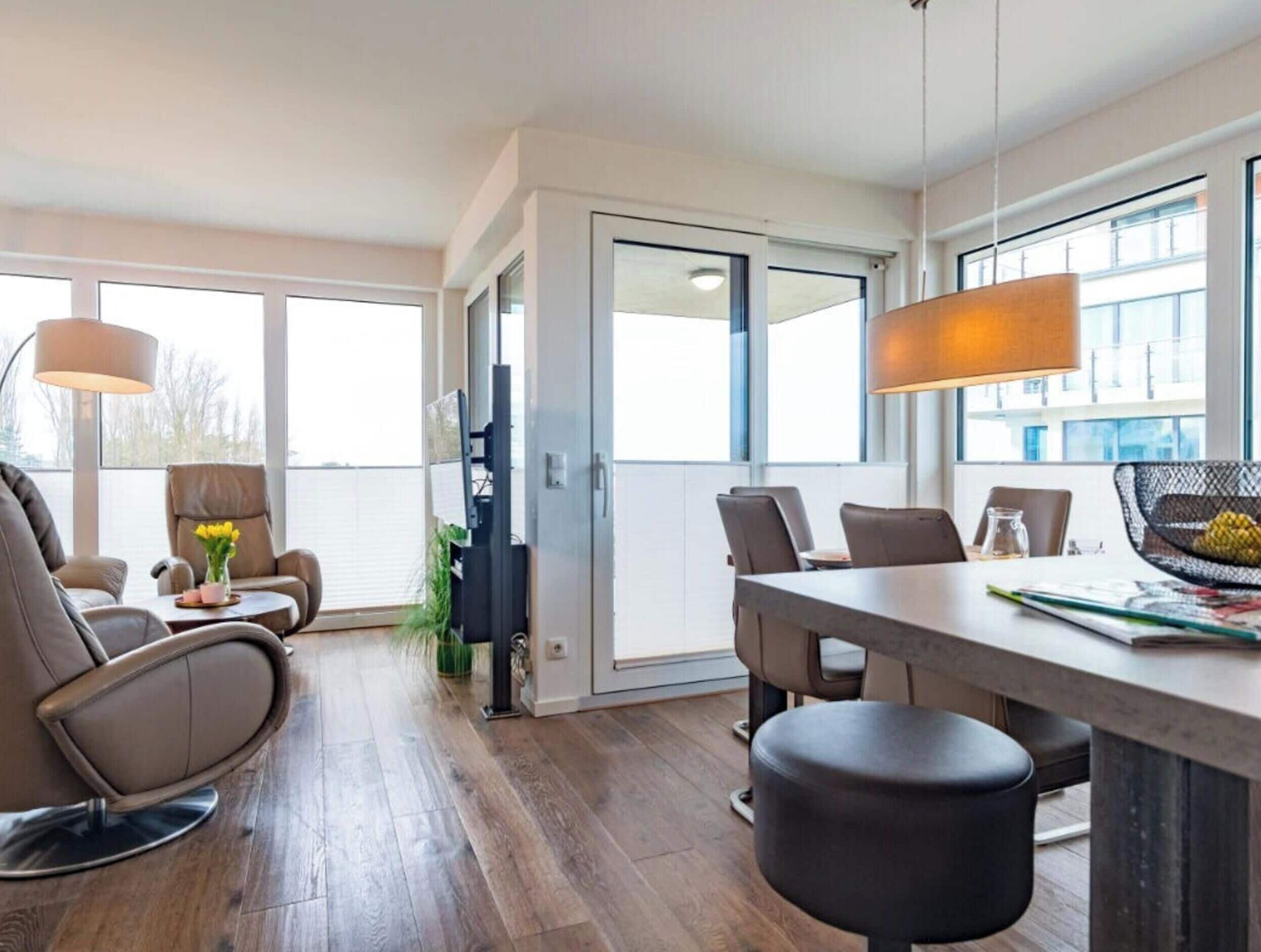 A modern interior with a dining area, seating, and a large window providing natural light.
