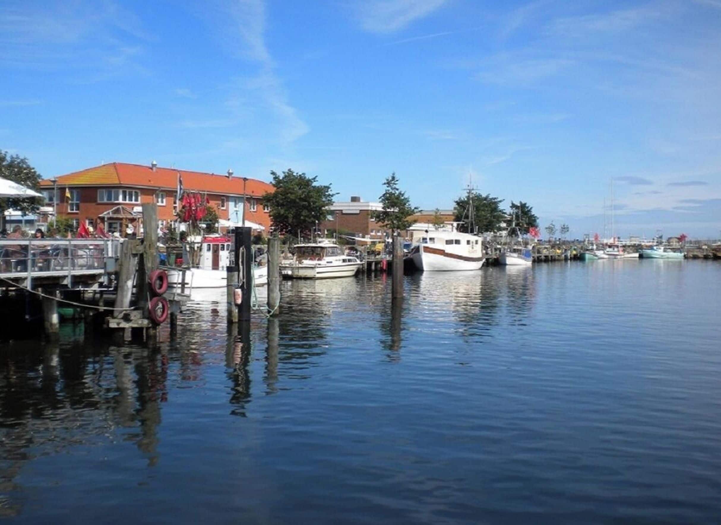 Een jachthaven met aan wal liggende boten, een gebouw met een rood dak en rustig water.