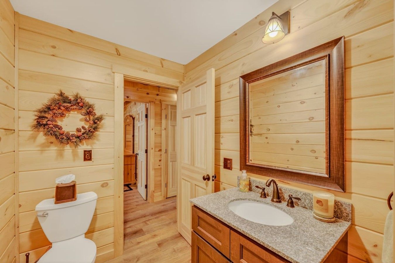 Een houten badkamer met een toilet, wastafel en spiegel.