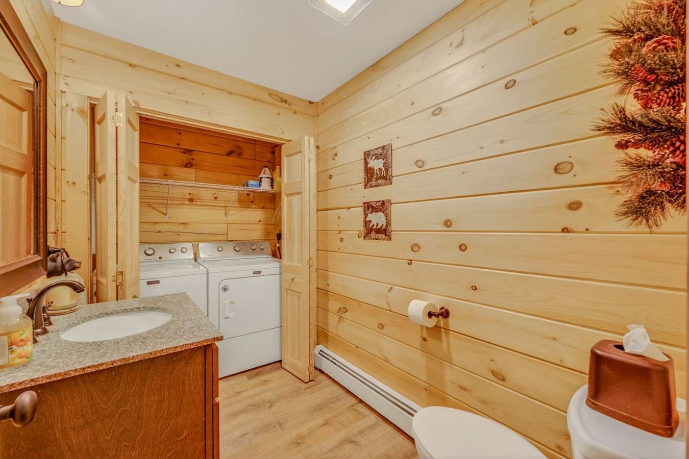 A compact wooden cabin with a kitchen area including a sink, stove, and washing machine.